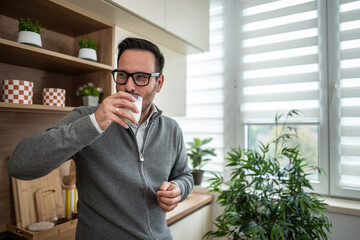 Man drinking fresh milk in modern kitchen at home