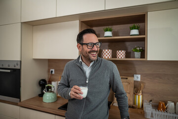 Happy man enjoying glass of milk in a modern kitchen