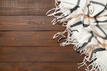 Plaid cashmere scarf on wooden background, top view