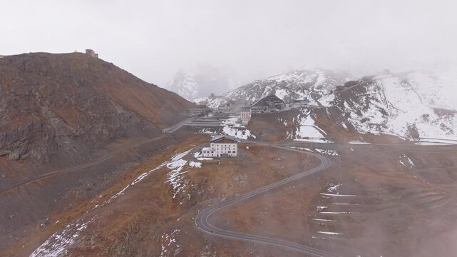 Drone view of foggy Stelvio mountain pass in fall, Italian Alps.