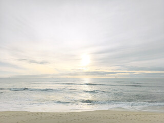Empty tropical beach at golden sunset. Serene ocean coast with warm glow and calm waves
