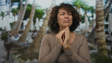Middle aged hispanic woman covers face with hands in forest wearing brown top; despair exhaustion...