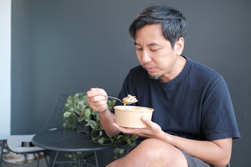 A man is eating from a bowl with a spoon