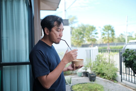 A man is drinking from a cup with a straw