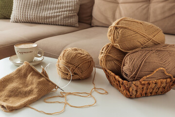 Cozy Living Room with Yarn, Pillows and Cup of Cappuccino on White Table