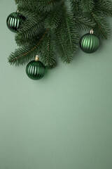 Green Christmas Ornaments Hanging on Pine Branches over Muted Green Background