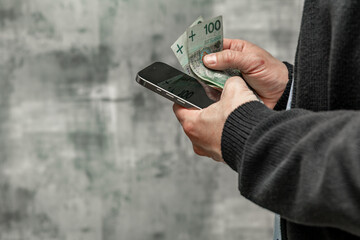 A man in a blue shirt and sweater holds money in his hand, counting the money