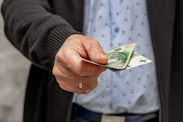 A man in a blue shirt and sweater holds money in his hand, counting the money