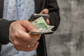 A man in a blue shirt and sweater holds money in his hand, counting the money