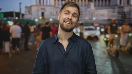 Man with visible face and trimmed beard tilts head and smiles while standing amidst a crowded...