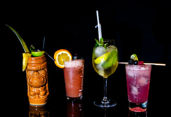 Diverse Set of Four Cocktails Including Tiki, Gin Tonic, and Tropical Drinks on Black Bar
