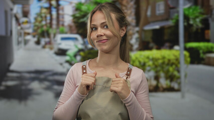 Fototapeta premium Blonde woman with clasped hands and gentle smile on street; uncertainty hesitation doubt introspection.