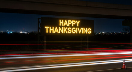 Illuminated sign displays "Happy Thanksgiving" over highway with blurred car light trails at night, representing seasonal travel greetings