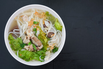 Bowl of Vietnamese noodle soup with meat and vegetables.