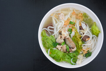 Bowl of Vietnamese noodle soup with meat and vegetables.
