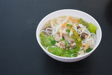Bowl of Vietnamese noodle soup with meat and vegetables.