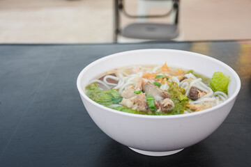 Bowl of Vietnamese noodle soup with meat and vegetables.
