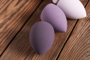 Makeup blender sponges in shape of eggs on wooden table