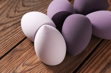 Makeup blender sponges in shape of eggs on wooden table