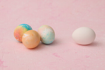Painted and unpainted Easter eggs on a pink background