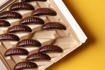 Box of chocolate candies on yellow background. Top view
