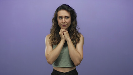 Woman clasping chin and gazing sideways in purple studio; contemplation doubt reflection...