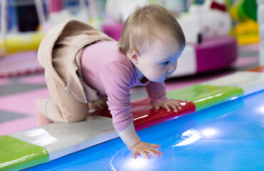 Little cute baby plays in a children's entertainment center