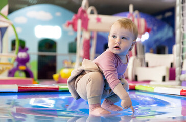 Little cute baby plays in a children's entertainment center