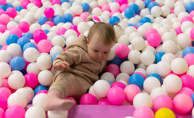 Obraz premium Cute little baby plays in a dry pool with balls at a children's entertainment center
