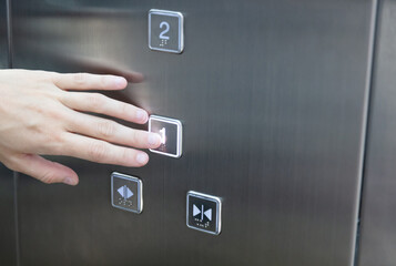 Hand presses elevator button choosing floor