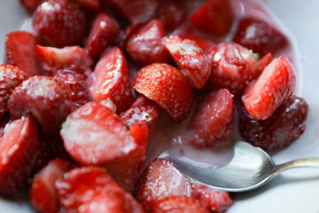 Slices of ripe tasty strawberries with milk syrup close-up