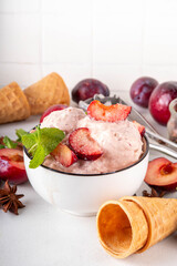 Winter flavor ice cream. Tasty Sugar plum  gelato in portioned bowl, with ice cream waffle cones, fresh and sugared plum fruits, copy space