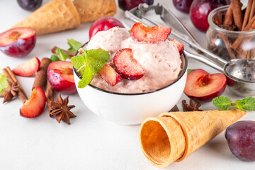 Winter flavor ice cream. Tasty Sugar plum  gelato in portioned bowl, with ice cream waffle cones, fresh and sugared plum fruits, copy space