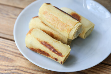 Roll pancakes with filling on plate, Wooden background