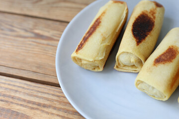 Roll pancakes with filling on plate, Wooden background