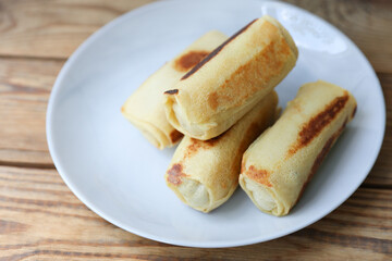 Roll pancakes with filling on plate, Wooden background