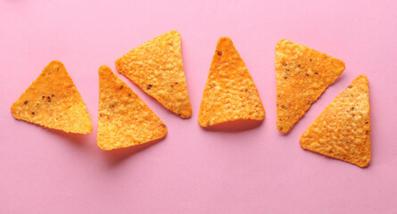 Triangular appetizing corn tortilla chips slices on pink background
