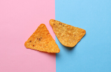 Triangular appetizing corn tortilla chips slices on pink blue background