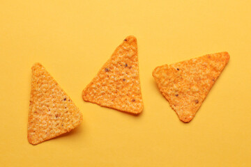 Triangular appetizing corn tortilla chips slices on yellow background