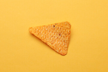 Triangular appetizing corn tortilla chip slice on yellow background