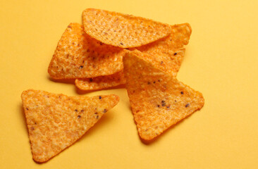 Triangular appetizing corn tortilla chips slices on yellow background