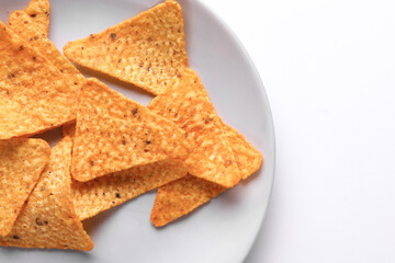 Triangular appetizing corn tortilla chips slices in plate on white background
