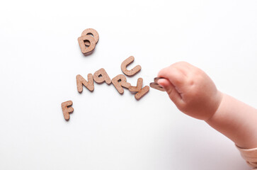 Baby hand holding wooden letters on white background