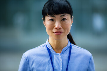 Confident adult woman with lanyard standing outdoors in city