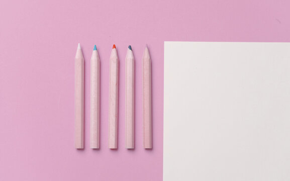 Wooden colored pencils and paper sheet on pink background. Creativity, art
