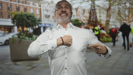 Man points finger to chest on street while showing hands and bracelets; surprise asserting identity.