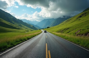 Naklejka premium Car travels on empty asphalt road through scenic mountain valley. Vehicle on summer road trip, journey into wild. Automobile moves along highway surrounded by green hills under cloudy sky.