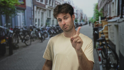 Fototapeta premium Man with finger to lips for silence on a city street framed by rows of parked bicycles and narrow buildings; hush.