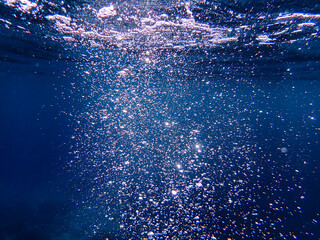 Ocean underwater rays of light background, under blue water sunlight. Underwater background, ocean or sea surface seen from under water. Rays of light beams, abstract marine backdrop. Nature landscape