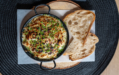 Deliciously baked cheese dip garnished with chives served alongside slices of toasted bread